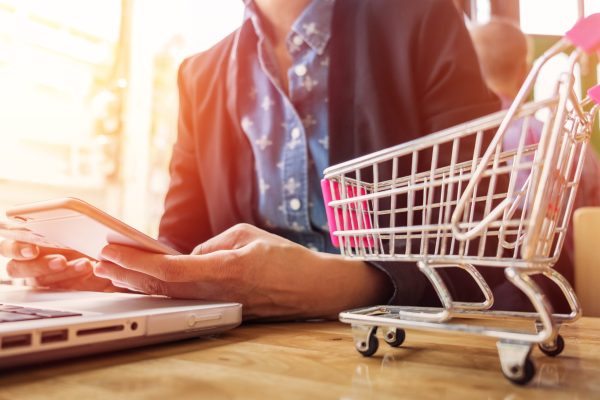 Cropped image of woman inputting card information and key on phone or laptop while shopping online.